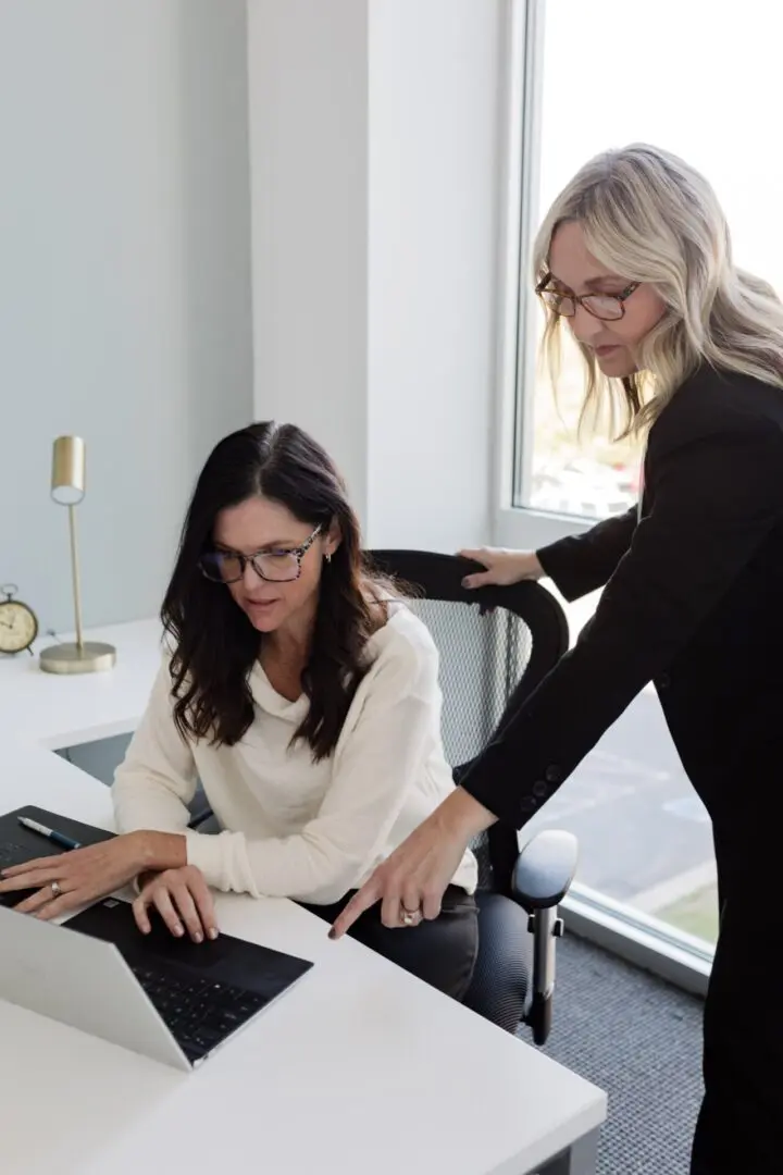 Two women are working on a laptop together.