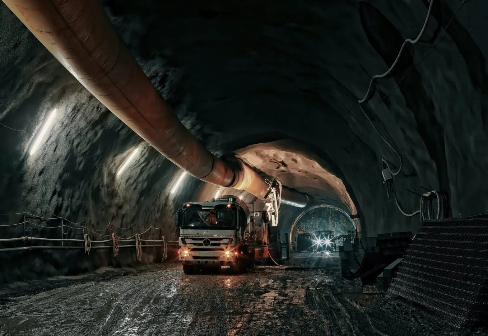 A person is holding onto the handle of a truck in an underground tunnel.