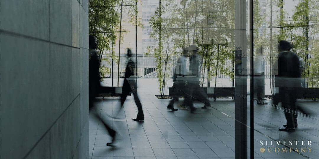 Blurred figures walking through glass doors.