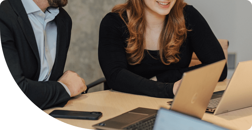 Two people working on laptops at a desk.