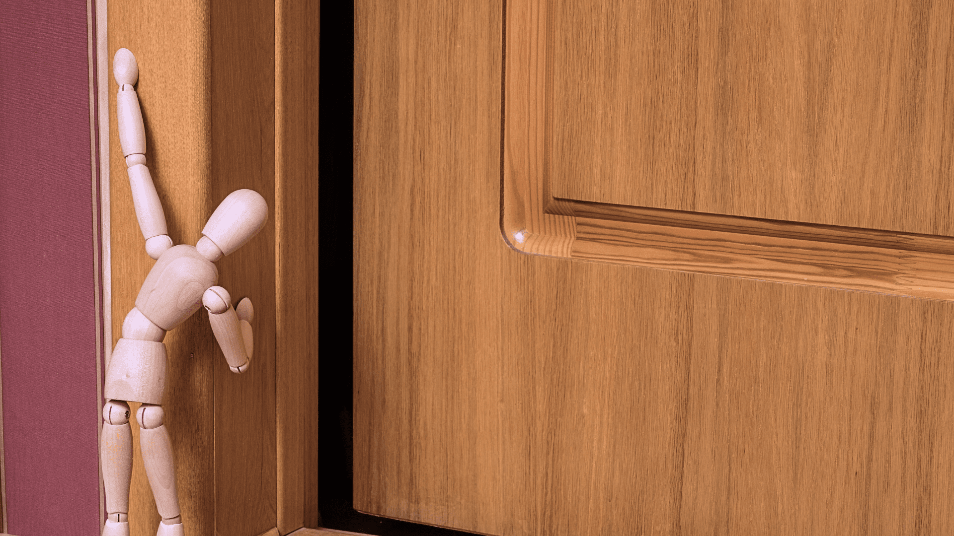 Wooden mannequin leaning against door frame.