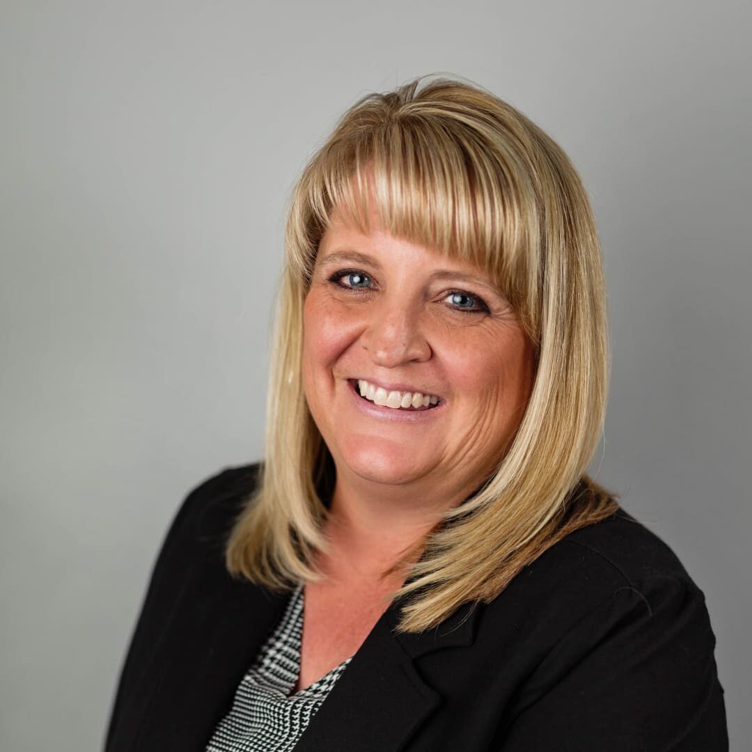 Smiling woman with blonde hair in a suit.