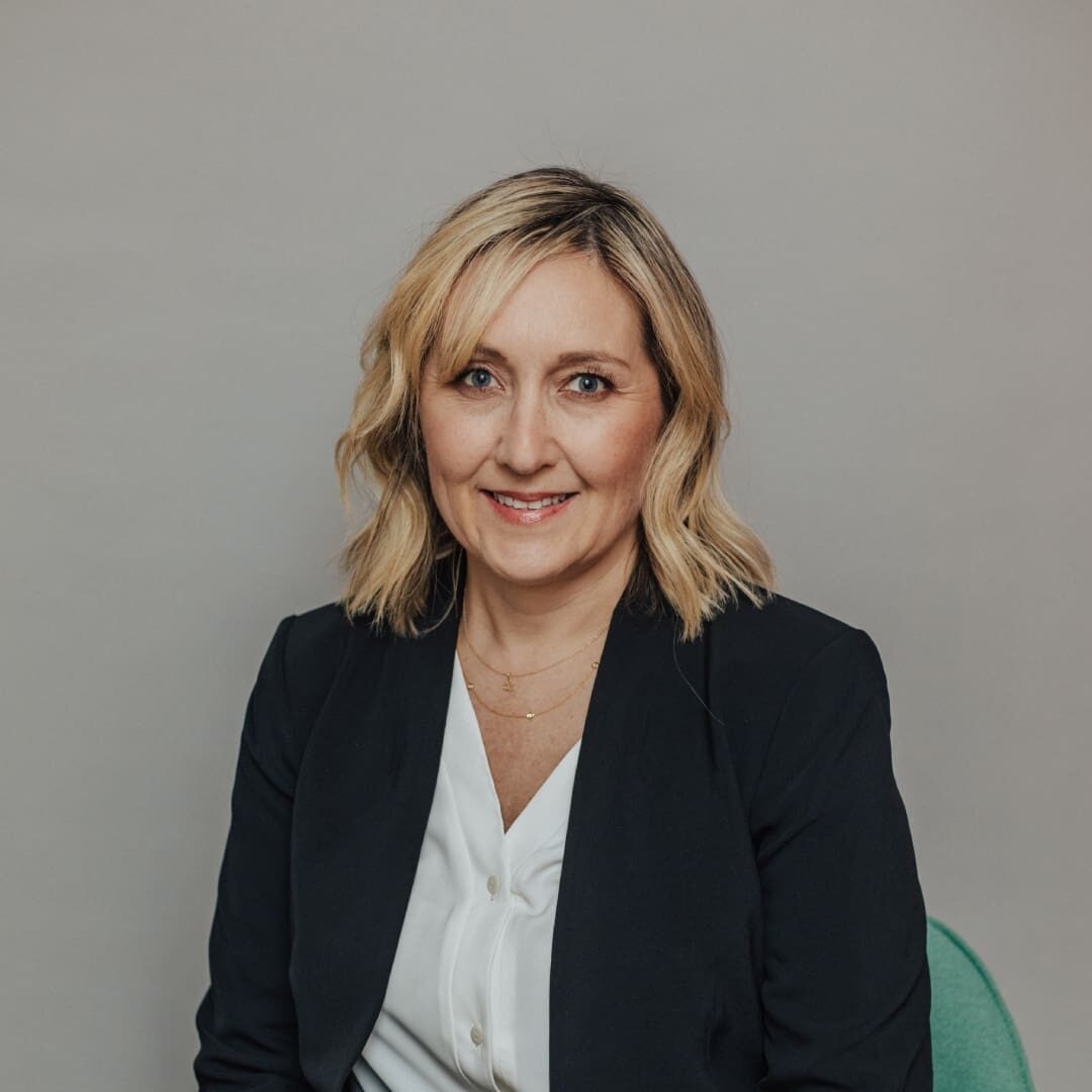 Smiling woman in black blazer and white shirt.