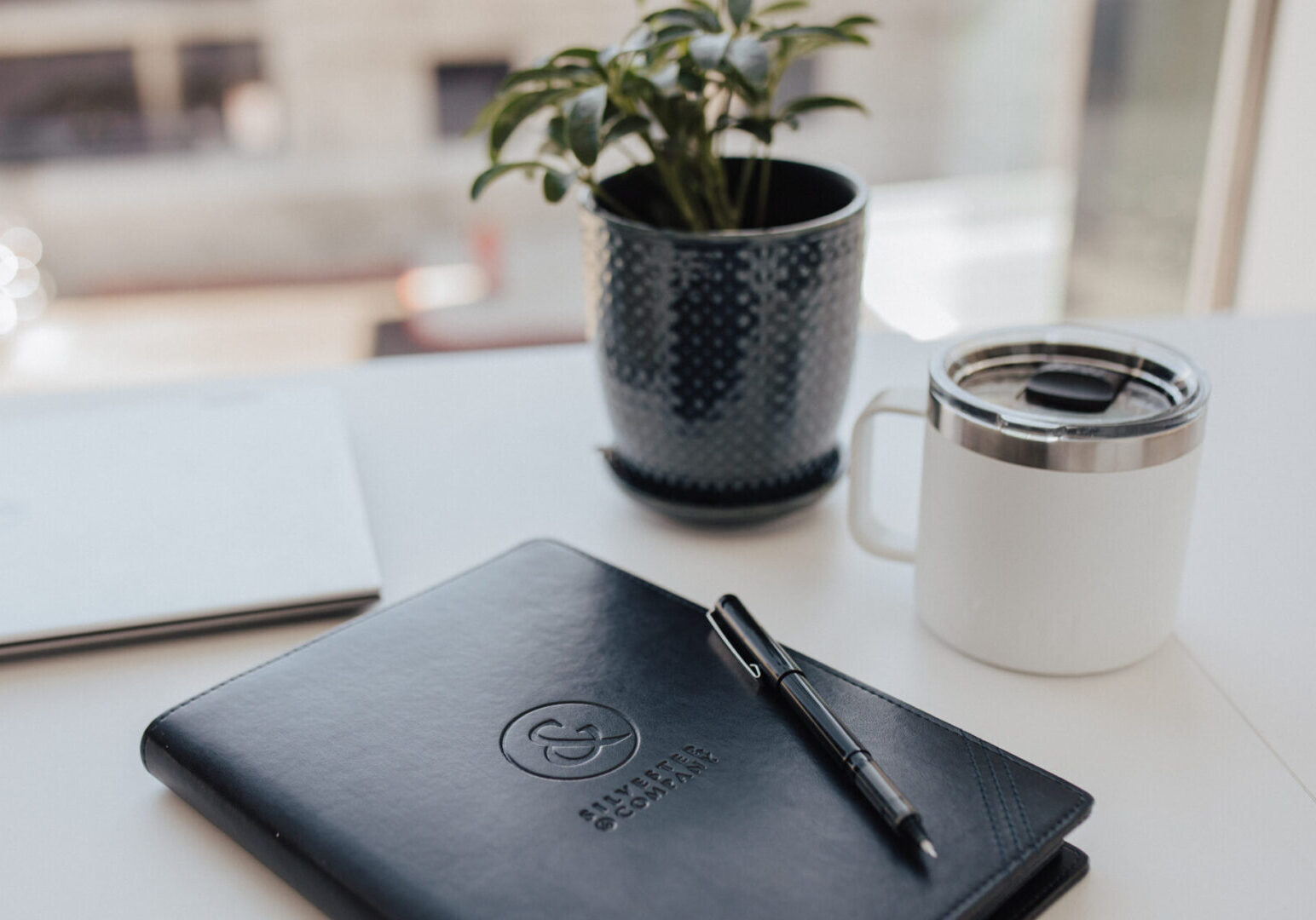 Black leather journal with pen and mug.