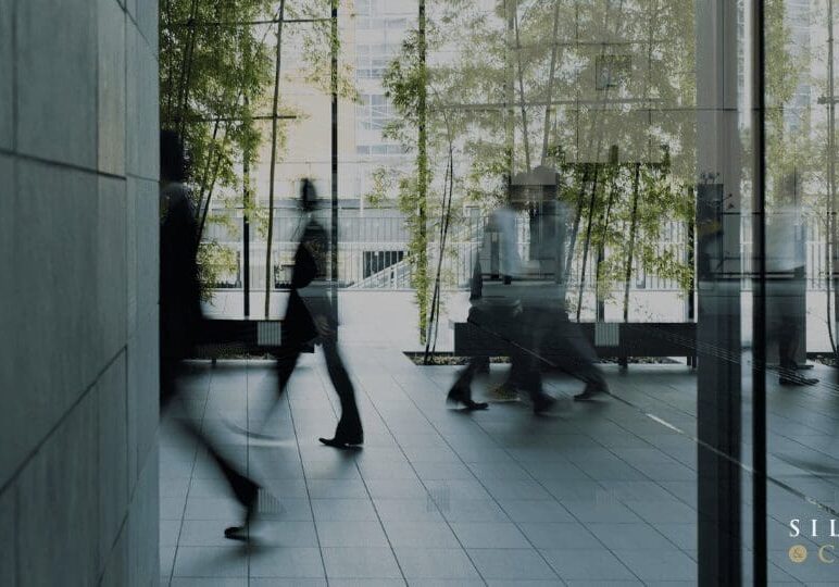 Blurred figures walking through glass doors.