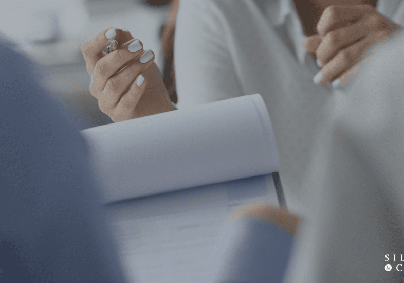 Person signing a document in meeting.