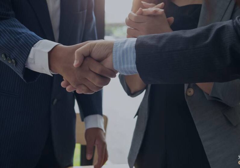 Two businessmen shaking hands in a meeting.